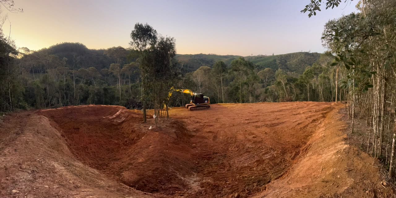 Escavadeira Caterpillar 312D no terreno preparado, no fim da tarde